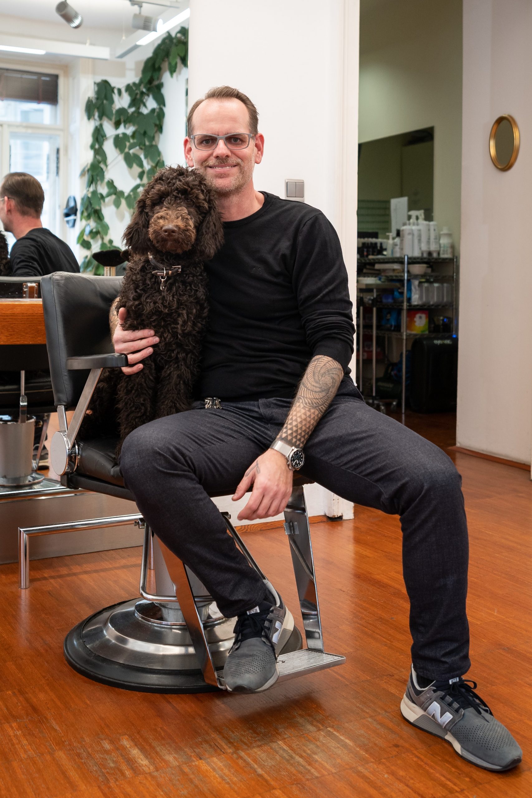 Saloninhaber Stefan mit Salonhund Alma auf seinem Arbeitsplatz